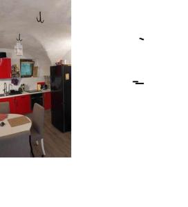 a kitchen with red cabinets and a black refrigerator at A L ESCALE PASSA PAÏS in Le Poujol-sur-Orb