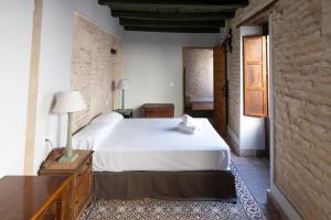 a bedroom with a white bed and a brick wall at Hospedería Monasterio de San Leandro in Seville