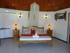 una camera da letto con un letto con due lampade sopra di Amitie Chalets Praslin a Grand Anse