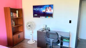 a room with a chair and a tv on the wall at Habitación 2 en Villa Mariaclaudia in Macas +6 photos