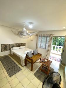 een slaapkamer met een bed, een stoel en een raam bij Karean Studio suites in Ukunda