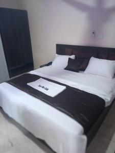 Una cama con una manta blanca y negra encima. en Tracer Wave Cabin, en Akwanga