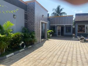 un patio de una casa con entrada para coches en Tracer Wave Cabin, en Akwanga