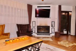 a living room with a table and a tv and a fireplace at Chez Vila in Prizren