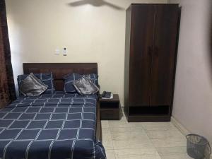 a bedroom with a bed with pillows and a cabinet at Tracer Wave Cabin in Akwanga +12 photos