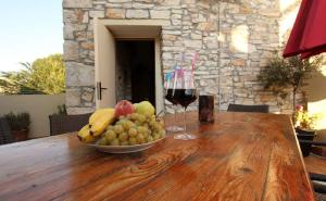 Eine Obstschale auf einem Holztisch mit einem Glas Wein in der Unterkunft Traditionelles Steinhaus mit Innenhof und Terrasse im Zentrum von Medulin, nicht weit vom Strand entfernt in Medulin