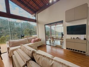 a living room with a couch and large windows at Casa 3 Quartos Recanto Buritis in Santa Teresa