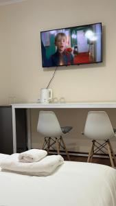 a tv on a wall above a bed with two chairs at Asman House in Alamedin