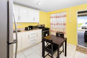 een keuken met een tafel en een kleine keuken met gele muren bij Mins from Beach • WiFi + AC • BBQ Grill in Vieux Fort