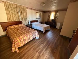 a bedroom with two beds and wooden floors at Springs Inn by Capital O I 25 in Colorado Springs