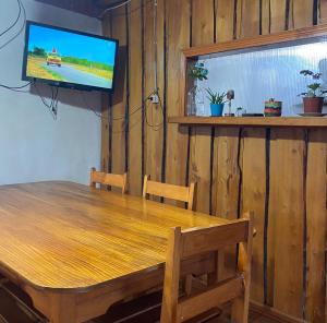 a dining room with a wooden table and a flat screen tv at La cascada in Futaleufú