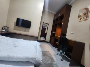 ein Schlafzimmer mit einem Bett, einem Schreibtisch und einem Fernseher in der Unterkunft D-Civya Home and Apartment in Morogoro