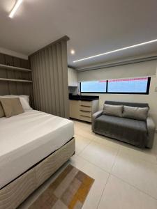 ein Schlafzimmer mit einem Bett und einer Couch darin in der Unterkunft Estudio Aurea Bauten 210 in Tambaú