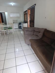 a living room with a brown couch and a kitchen at Casa em Itapema in Itapema