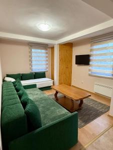 a living room with a green couch and a table at Ski kuca Elbrus in Jahorina