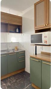 a kitchen with green cabinets and a microwave at Apto aconchegante, central, prox ao carrefour in Santa Maria