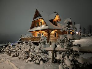 a log cabin with snow on its roof at Ostoja Spokoju in Kościelisko +4 photos