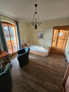 a bedroom with a bed and two chairs and a chandelier at Braukeller Fattigau in Oberkotzau
