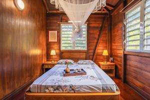 Un dormitorio con una cama en una habitación de madera. en Villasticreole, en Deshaies 93 fotos más