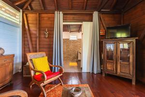 Una sala de estar con una silla y un televisor. en Villasticreole, en Deshaies