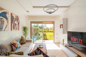 un salon avec un canapé et une télévision dans l'établissement Appartement de prestige au golf, à Marrakech