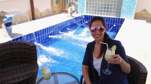 a woman holding a drink in front of a pool at P Quattro Relax Hotel in Wadi Musa