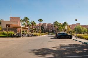 une voiture garée sur le bord d'une rue avec des motos dans l'établissement Appartement de prestige au golf, à Marrakech