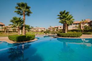 une piscine avec des palmiers dans un complexe hôtelier dans l'établissement Appartement de prestige au golf, à Marrakech