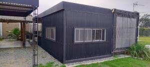 a black building with two windows in a yard at Hostal del Sol Rosario in Rosario