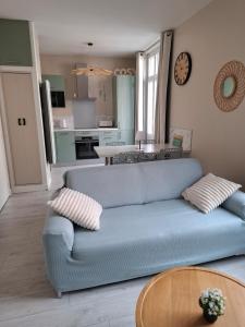 a living room with a blue couch and a table at Le Cosy in Mers-les-Bains