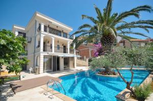 a swimming pool in front of a house with a palm tree at Villa St.George in Petrovac na Moru