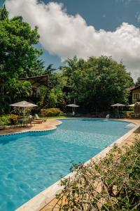 a large swimming pool with chairs and umbrellas at Recanto da Mata Pipa in Pipa