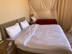 a bedroom with a bed with white sheets and pillows at Lunara rum camp in Wadi Rum