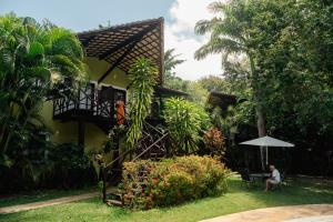 a person sitting under an umbrella in front of a house at Recanto da Mata Pipa in Pipa