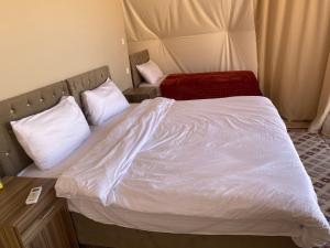 a bedroom with a bed with white sheets and pillows at Lunara rum camp in Wadi Rum