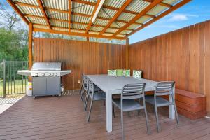 a patio with a table and a grill on a wooden deck at Chardonnay Escape in Pokolbin