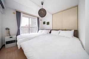 two white beds in a room with a window at Nakajima Park Mansion - Vacation STAY 20417 in Toyohira