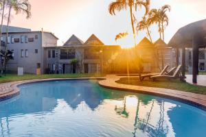 a swimming pool in front of a building with palm trees at The Bridge, Apartment 67 in St Lucia