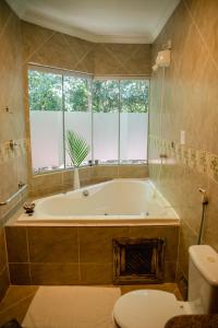 a bathroom with a tub and a toilet and a window at Recanto da Mata Pipa in Pipa