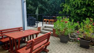 a patio with two benches and a table and some plants at Ezee Rider Apartmanok in Sárvár
