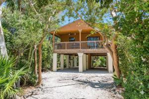 a house with a large deck in the middle of trees at The Florida Keys Treehouse in Marathon, FL in Marathon