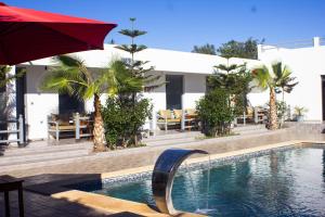 a swimming pool with a red umbrella and tables and chairs at Dar naima in Al Ghar