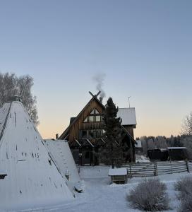 uma cabana de madeira na neve com telhados cobertos de neve em Shaman Village - Resort & Glass Igloos em Rovaniemi