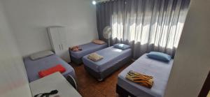 een kamer met drie bedden en een raam bij Hotel Pousada Liberdade in Pindamonhangaba