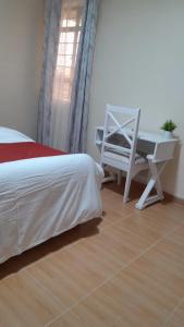 a bedroom with a bed and a desk and a chair at HERIJ Staycation kitengela in Kitengela 