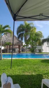 a person laying on the grass under an umbrella next to a swimming pool at Casas Diamante in Xochitepec +43 photos