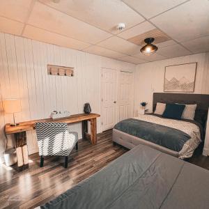 a bedroom with a bed and a desk and a bed and a chair at Auberge Le Chic in Maniwaki