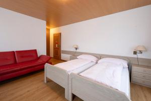 a bedroom with two beds and a red couch at Gasthof zur alten Post in Büren an der Aare
