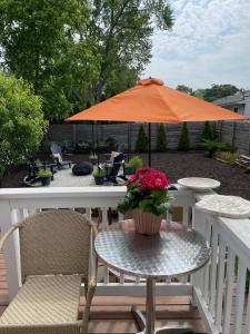 une table et des chaises avec un parasol orange sur une terrasse dans l'établissement Eastside Abode - Local Living Weekly & Monthly Rentals Only Contact for Monthly Rates, à Grand Haven