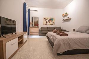 a bedroom with a bed and a couch and a television at Spacious 3-Bedroom Apartment with Balconies-Central Sliema in Sliema